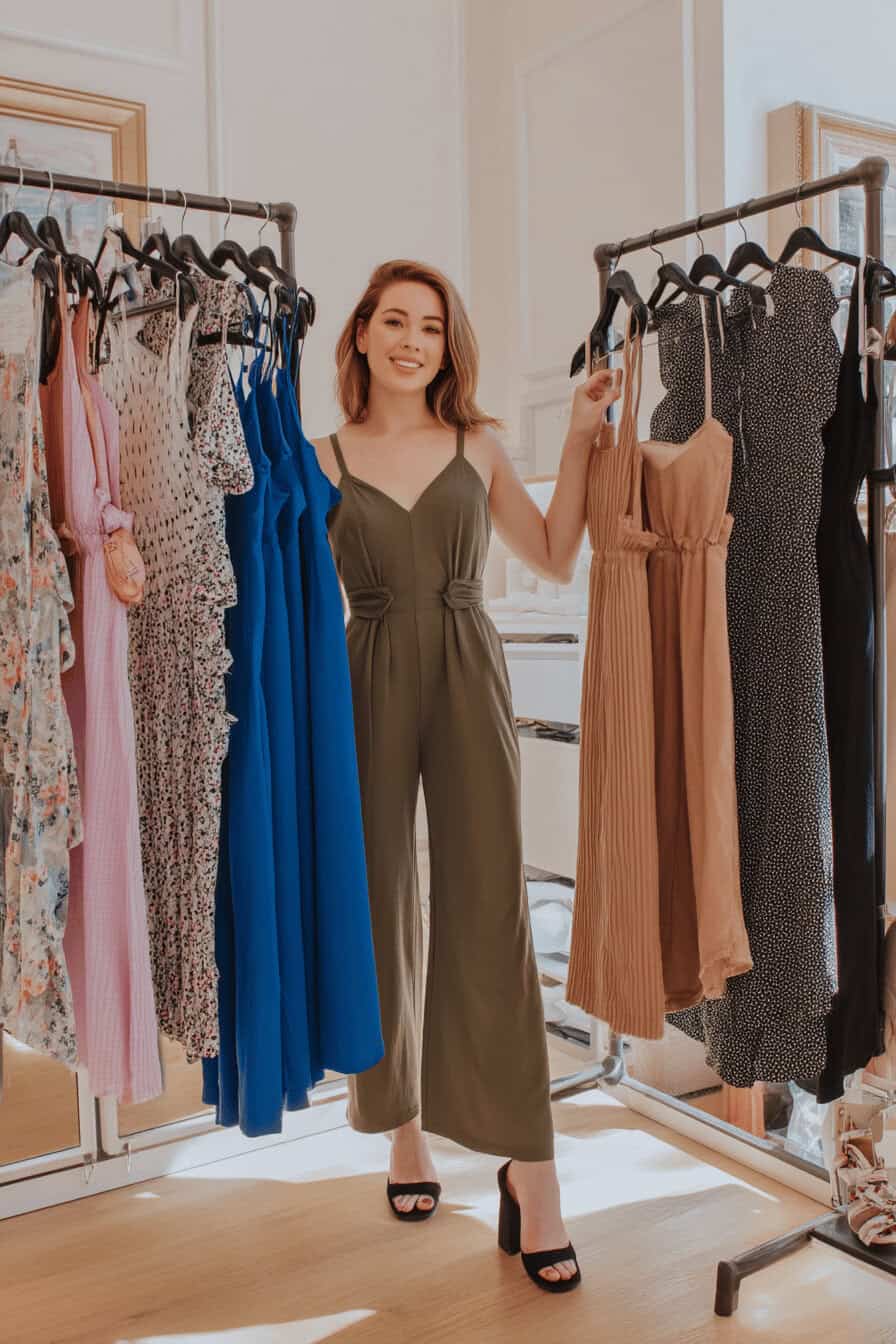 Frau in elegantem Jumpsuit steht zwischen Kleiderstangen mit Sommerkleidung.