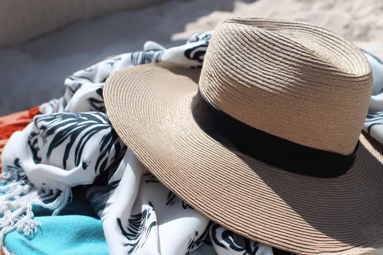 Sommerhut auf gemustertem Tuch am Strand.
