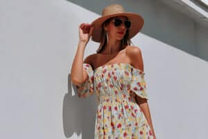 Frau in Sommerkleid und Hut vor Wand