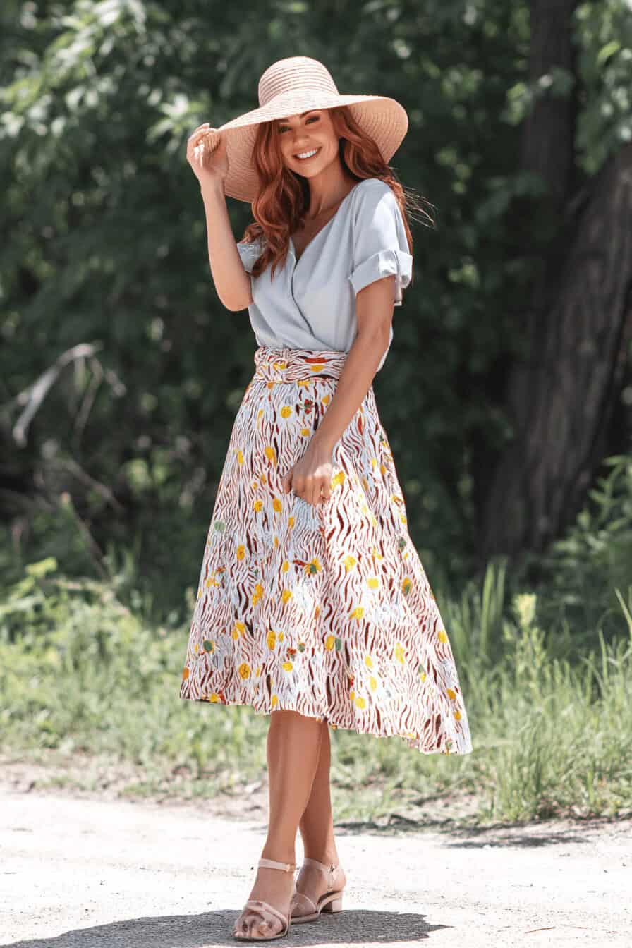 Dame in A-Linie Rock mit floralem Muster und Strohhut.