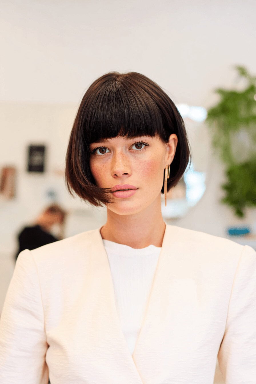 Modischer Kurzhaarschnitt mit geradem Pony bei einer Person.