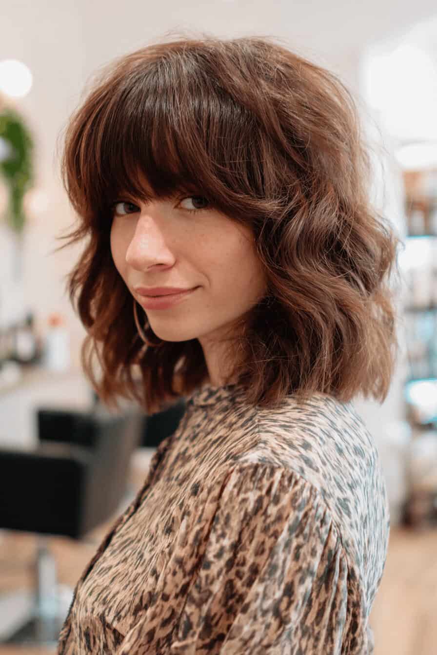 Frau mit schulterlangem, gewelltem Haar und Pony im Salon.