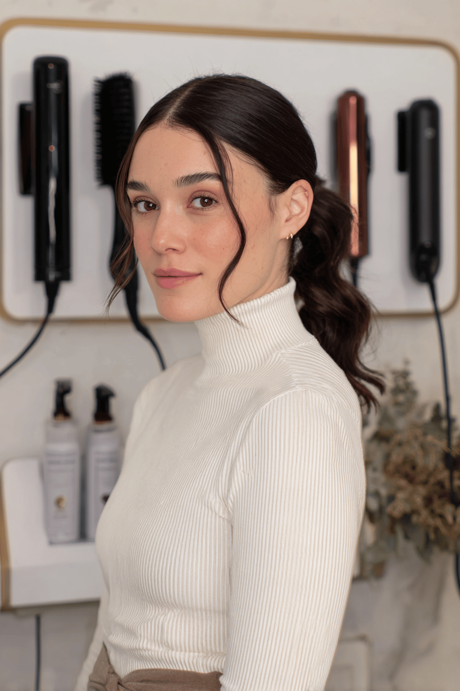 Frau mit einem Sleek Ponytail und Mittelscheitel, der elegant zurückgebunden ist.