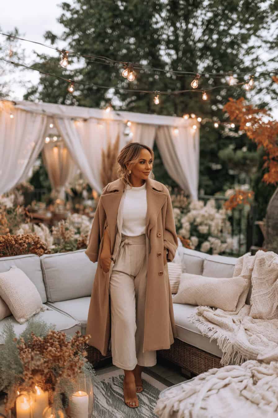 Frau in elegantem Kamelmantel bei stilvoll dekorierter Gartenparty im Herbst