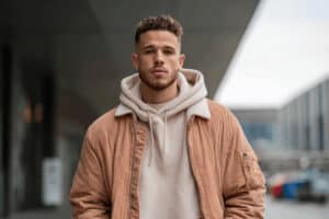 Mann in hellbrauner Cordjacke und beigefarbenem Hoodie