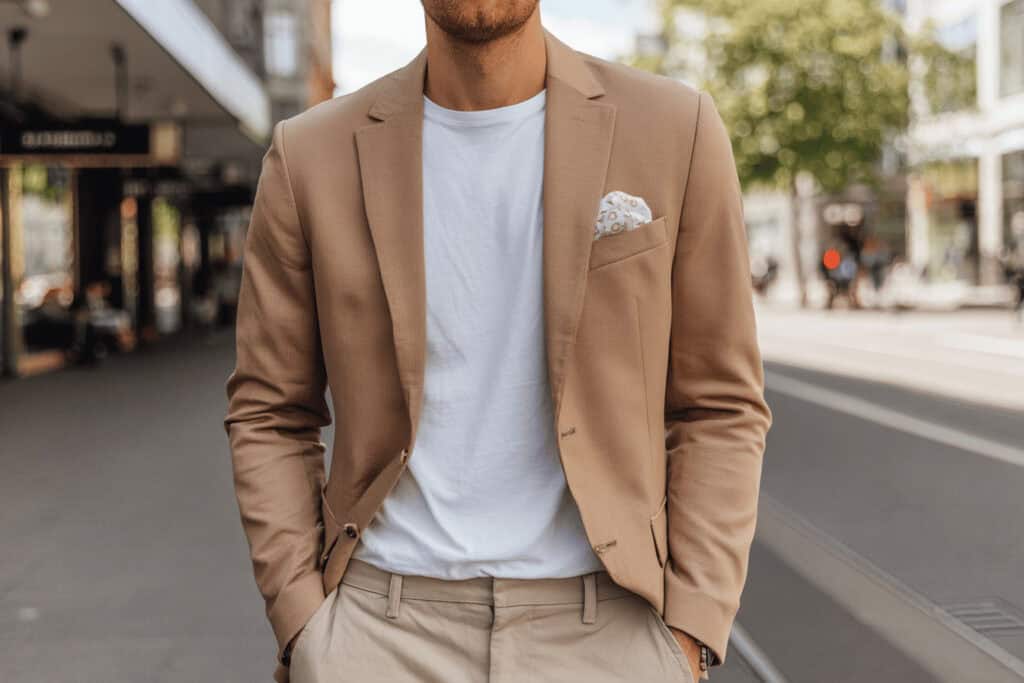 Mann mit beigem Sakko, weißem T-Shirt und Einstecktuch