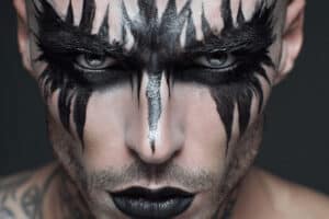 Mann mit schwarzem Halloween Make-up in Tribal-Optik