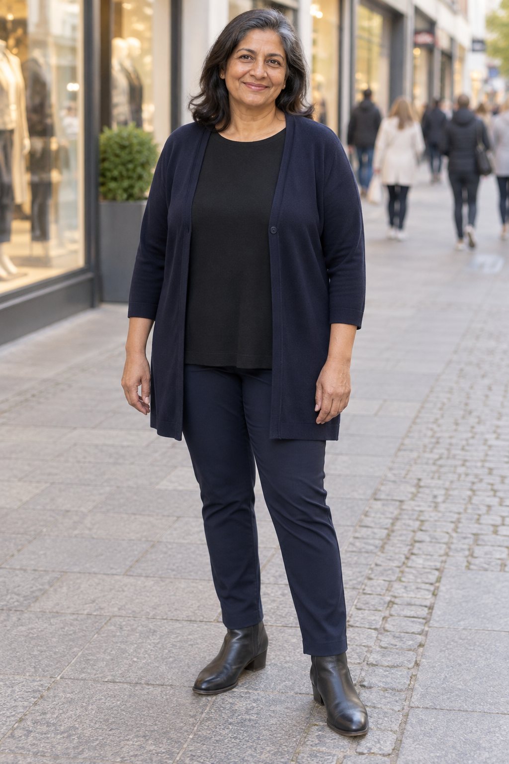 Frau trägt Dunkelblaue Longstrickjacke zu schmaler Hose – Einkaufsbummel