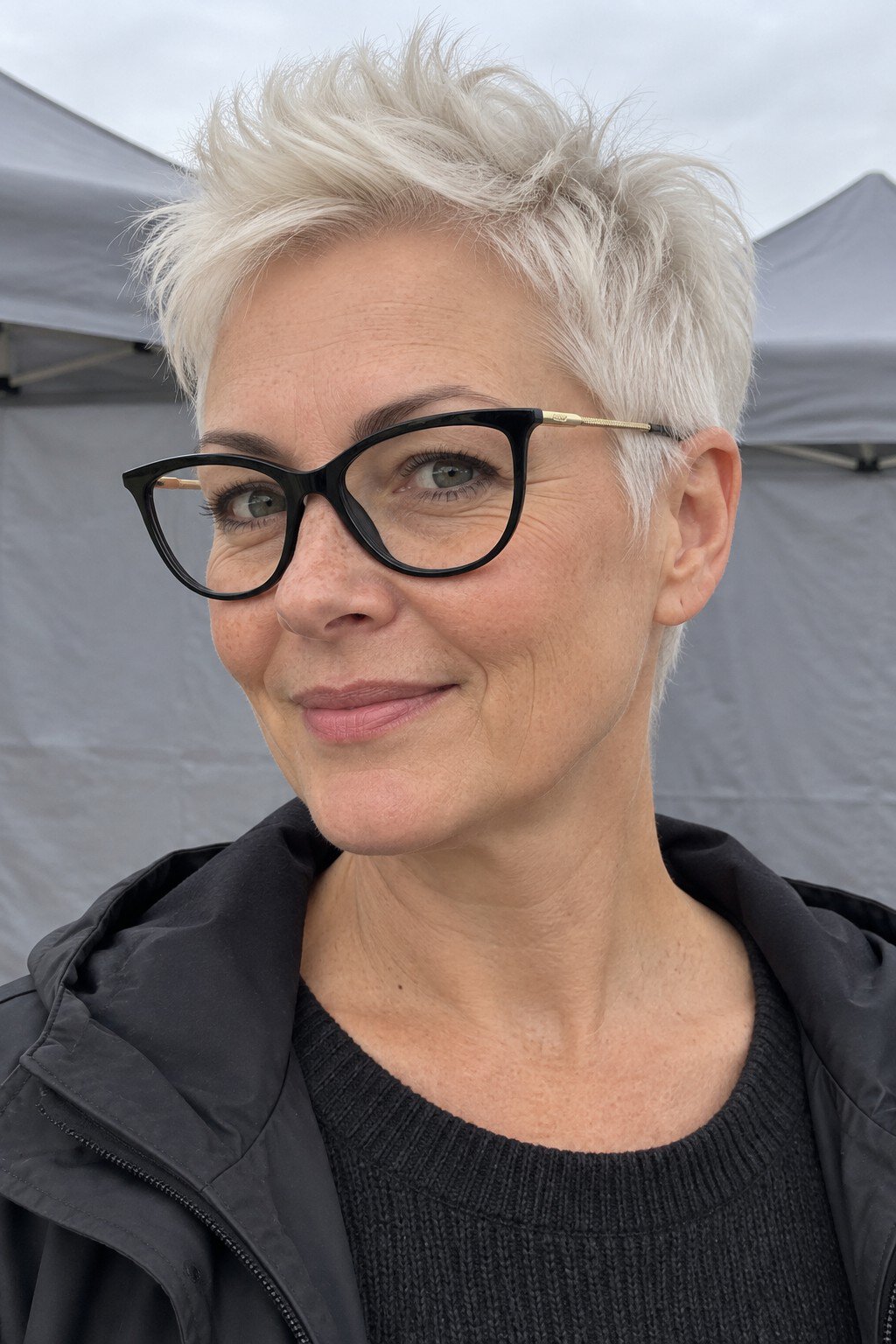 Frau mit Brille: Sehr kurzer Pixie mit hochgeföhntem Oberkopf und schwarzer Katzenaugenform